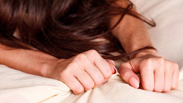 Woman's hands grabbing bed sheets