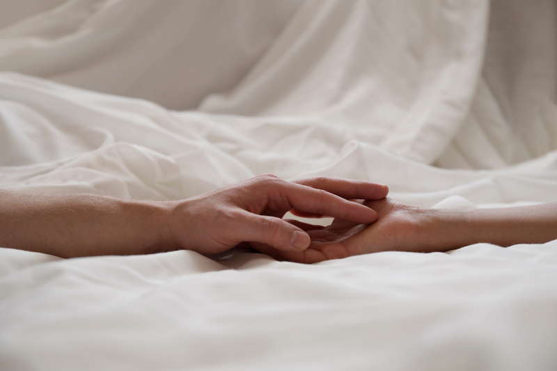 Couples hands touch on bed