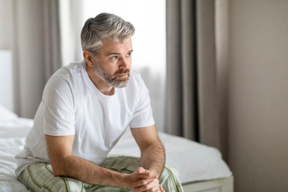 Anxious man sitting on hand hands clasped