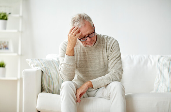 Stressed man sitting on white sofa