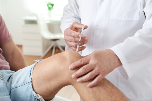 Doctor administering injection in patient's knee