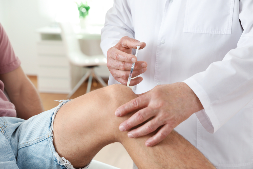 Doctor administering injection in patient's knee