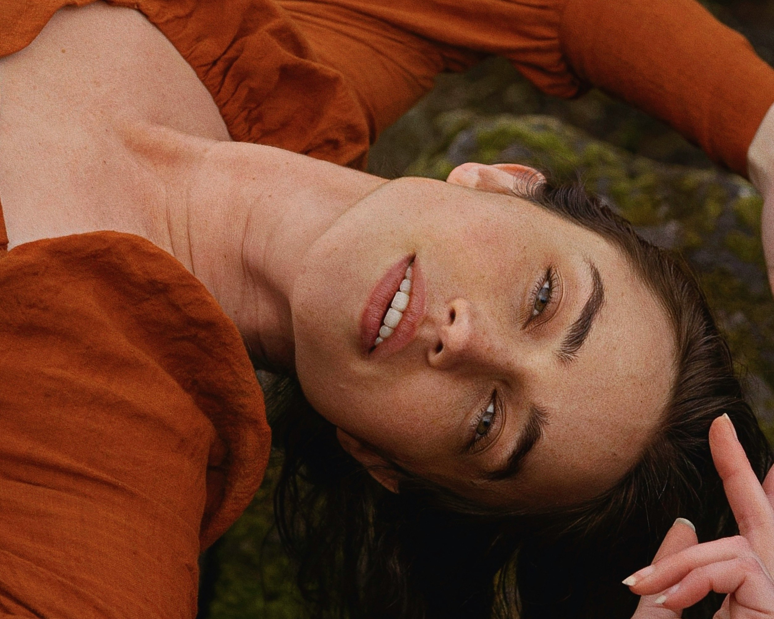Attractive woman sprawled on back wearing orange top