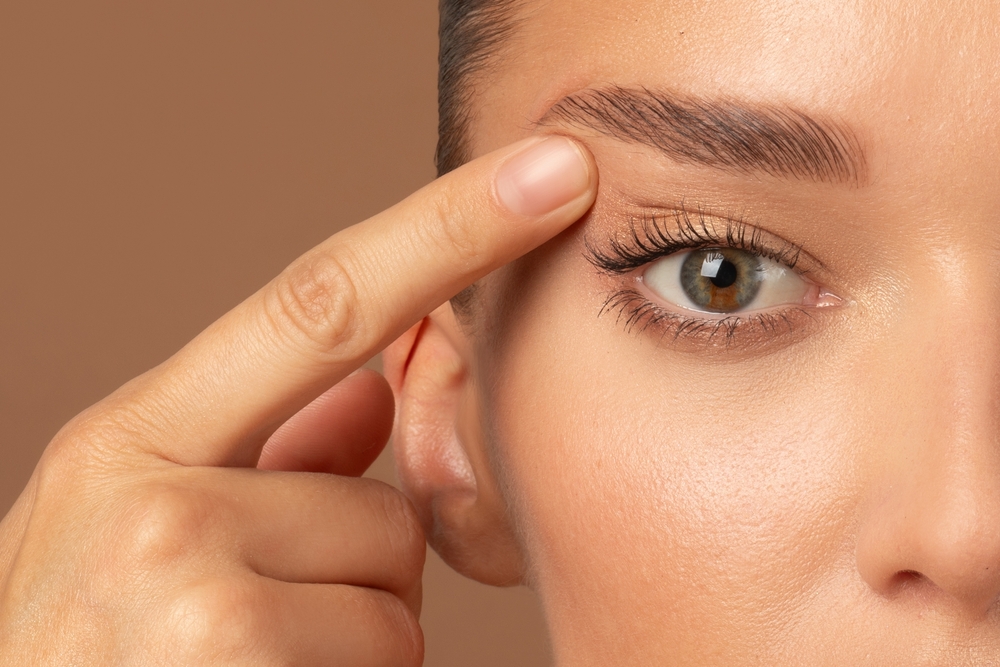 Woman lifting up folding skin above the eye