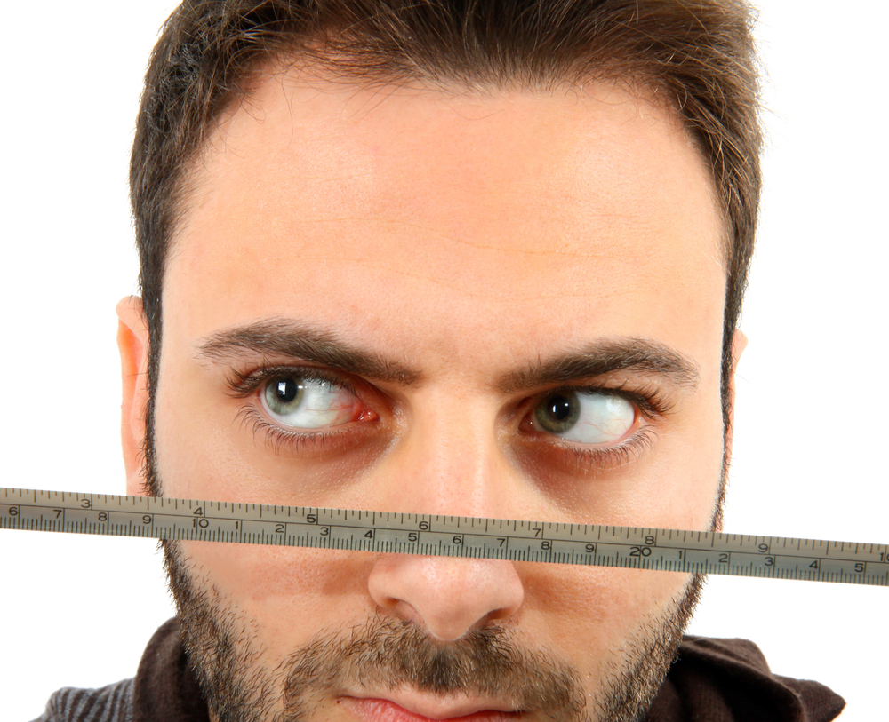 Close up of man's face with tape measure beneath eyes