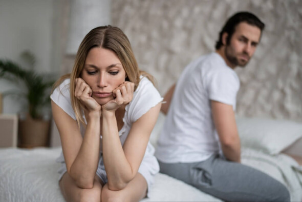 Stressed couple in bed facing intimacy issues due to hormone imbalance affecting libido